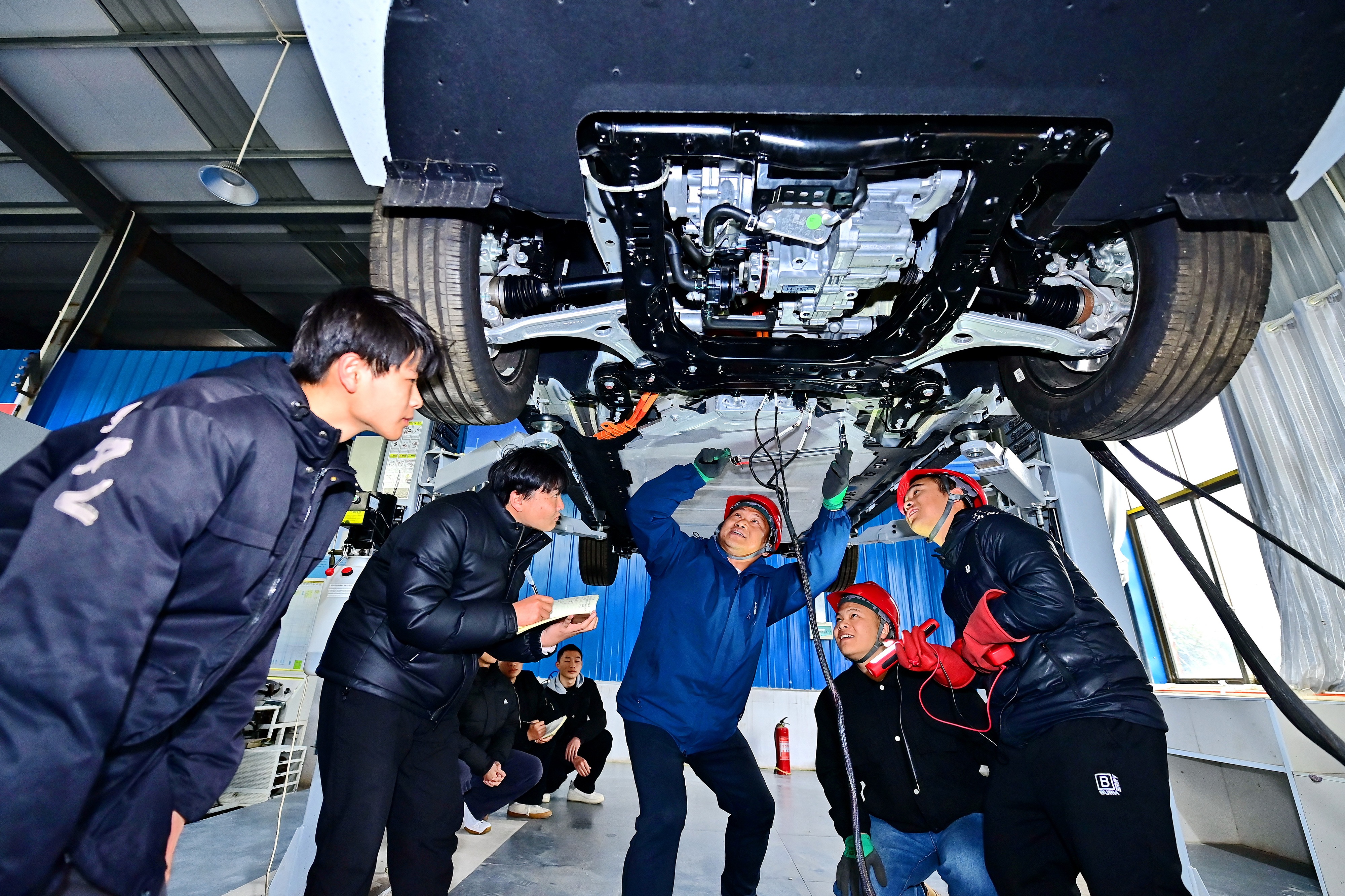 2025年2月17日，江西省宜春市，丰城市的一所技工学校实训基地内，新能源汽车运维专业学生在老师的指导下学习新能源汽车电池包检修技术。